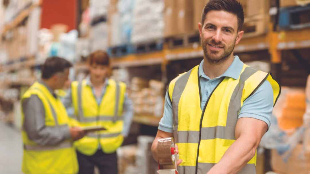 Warehouse team wearing reflective vests and smiling