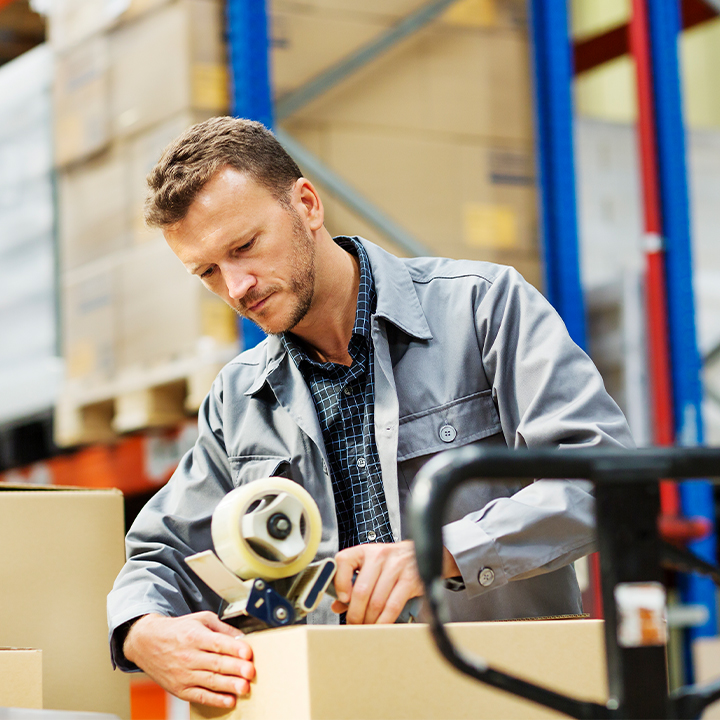 warehouse worker taping a box in a warehouse