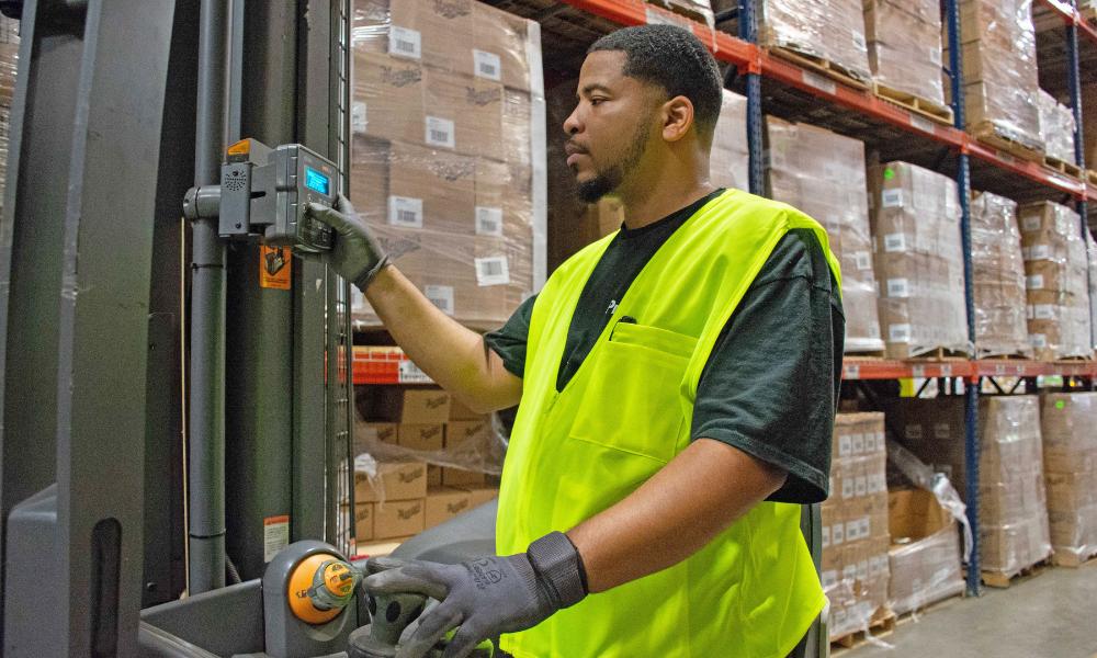 man in safety vest checking settings on forklift