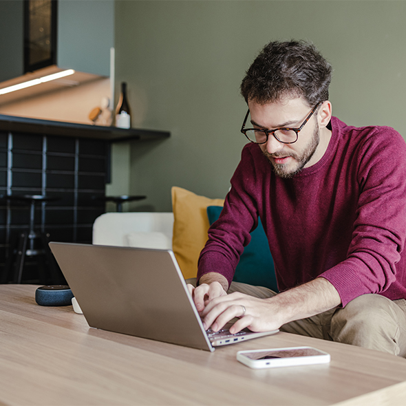 man in red shirt using laptop