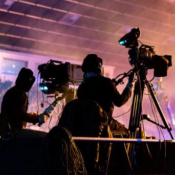 two cameramen operating cameras at a concert 