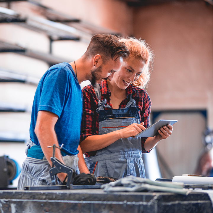 two people in a manufacturing line looking at a tablet