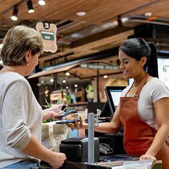 woman checking out of grocery store tapping her phone to pay the cashier 