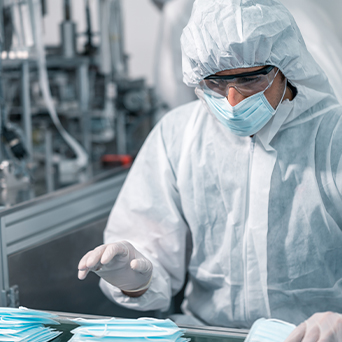 Worker wearing PPE and looking at masks 