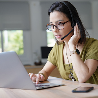 woman wearing glasses and headset working on a laptop