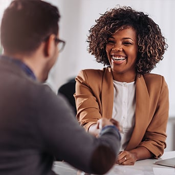 man and woman sitting across from each other at a table shaking hands