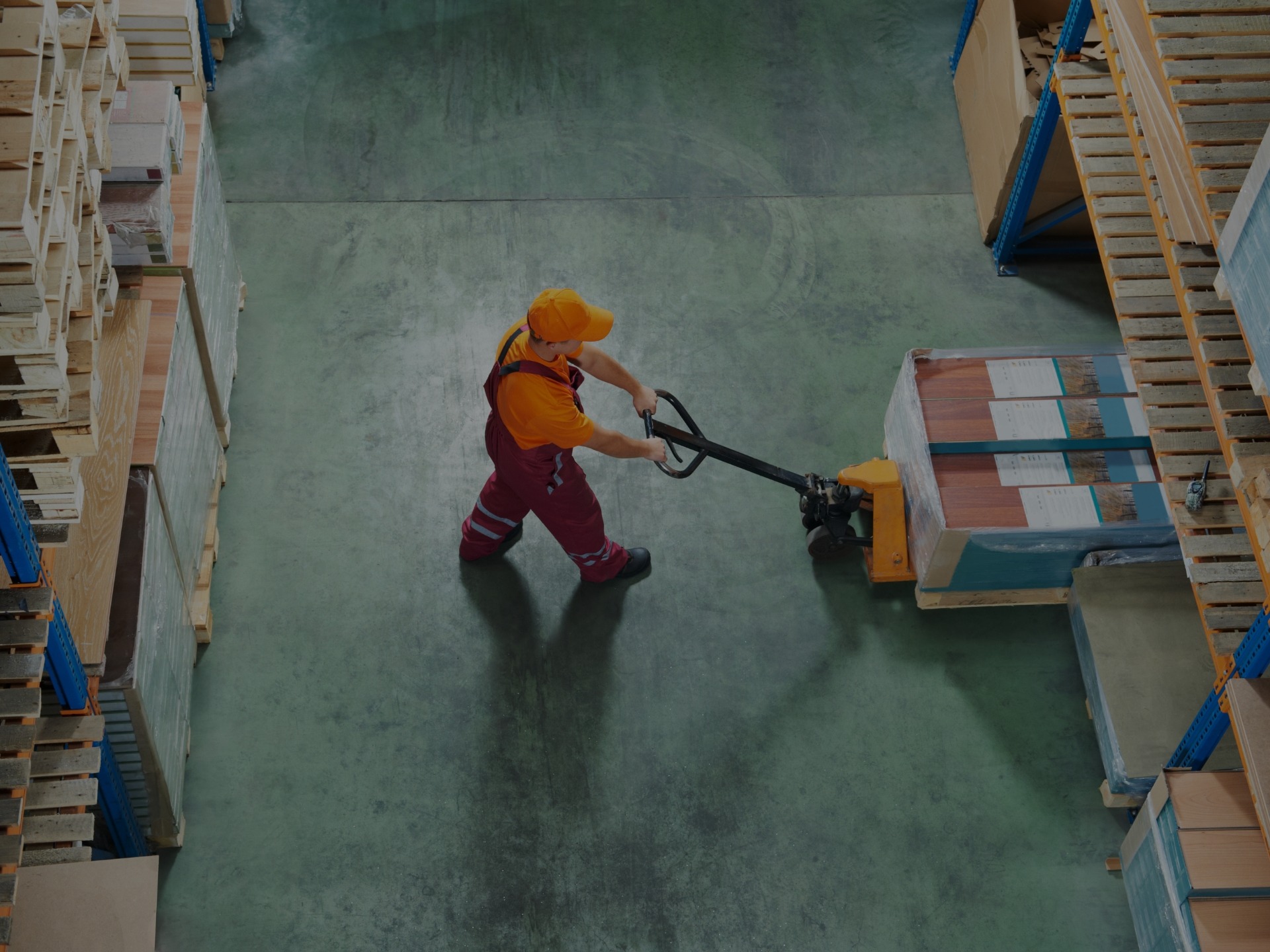 Warehouse working using a power jack to move a box through the warehouse.