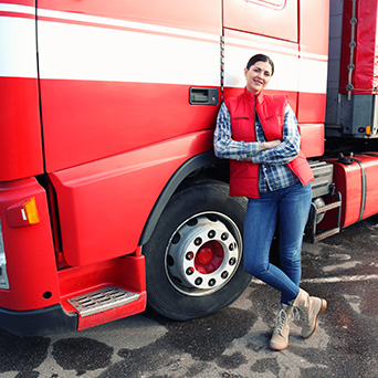 Truck driver leaning against a red truck