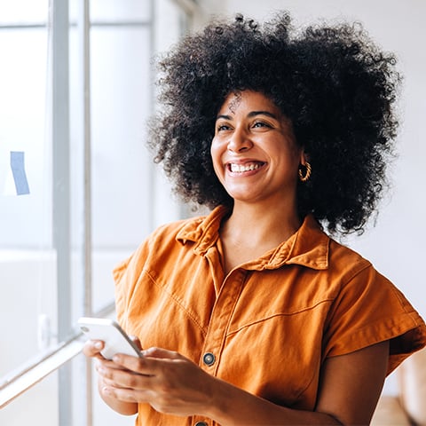 woman in business attire smiling while looking out the window